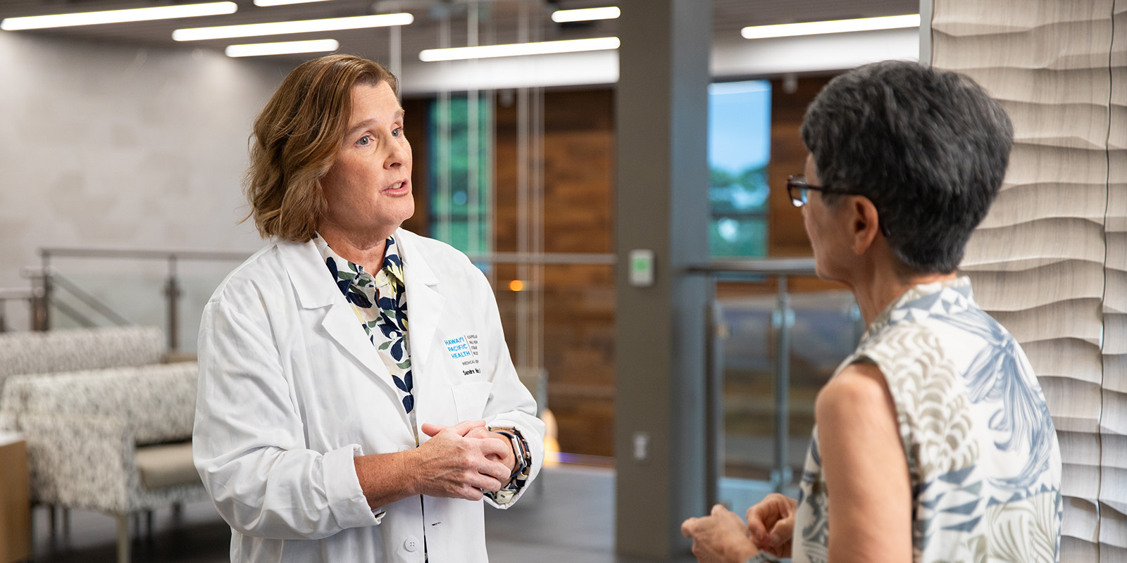 Doctor in white coat speaking with a patient in the lobby of a medical clinic.