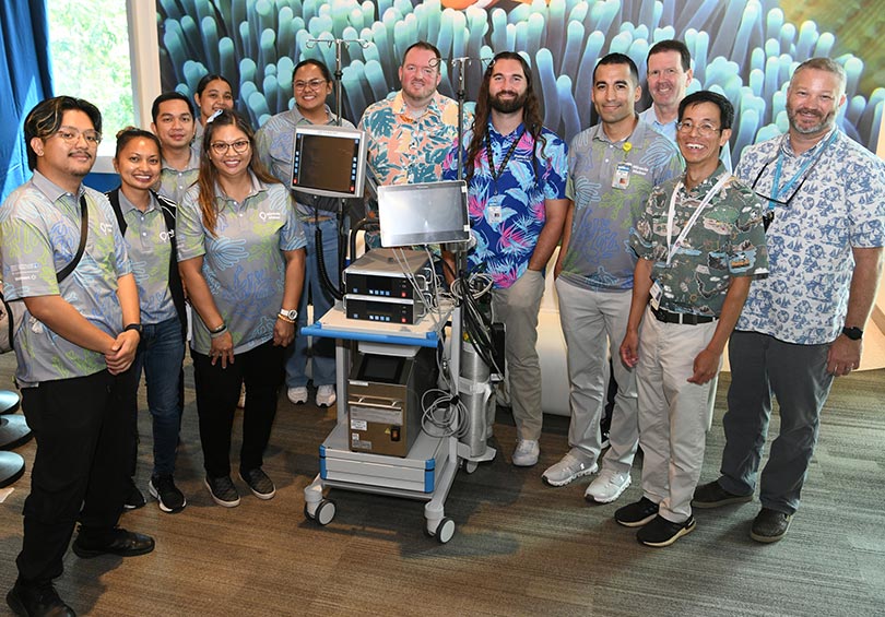 Group of fundraiser volunteers posing and smiling behind a new ECMO machine.