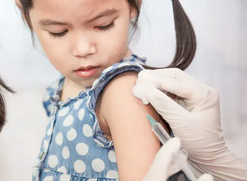 A child receives a vaccination in her arm.