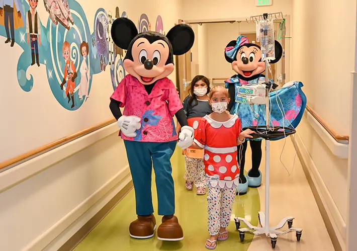 Disney character mascots walking down the hallway with patients.