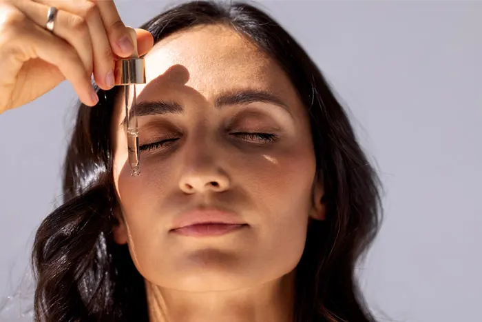 Woman putting serum on her face.
